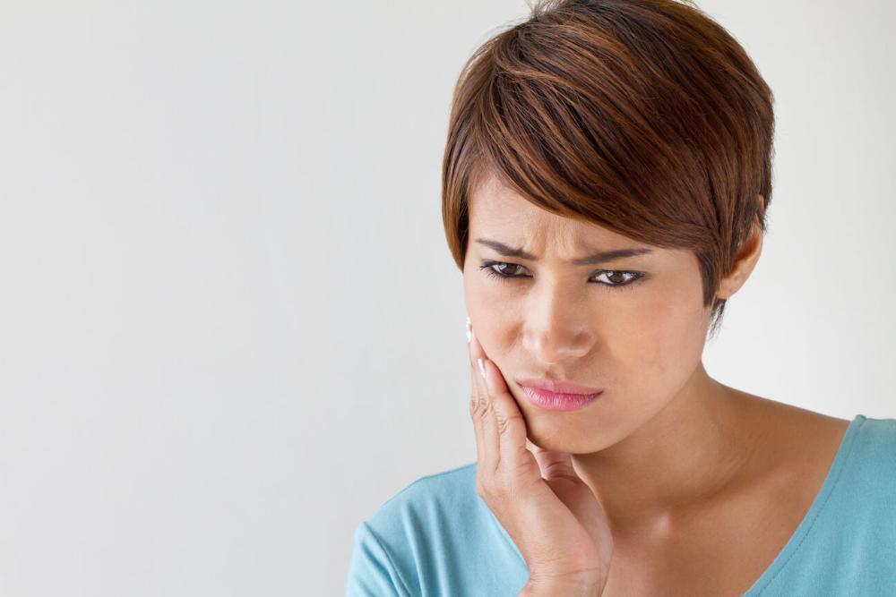 woman holding chin from dental emergency