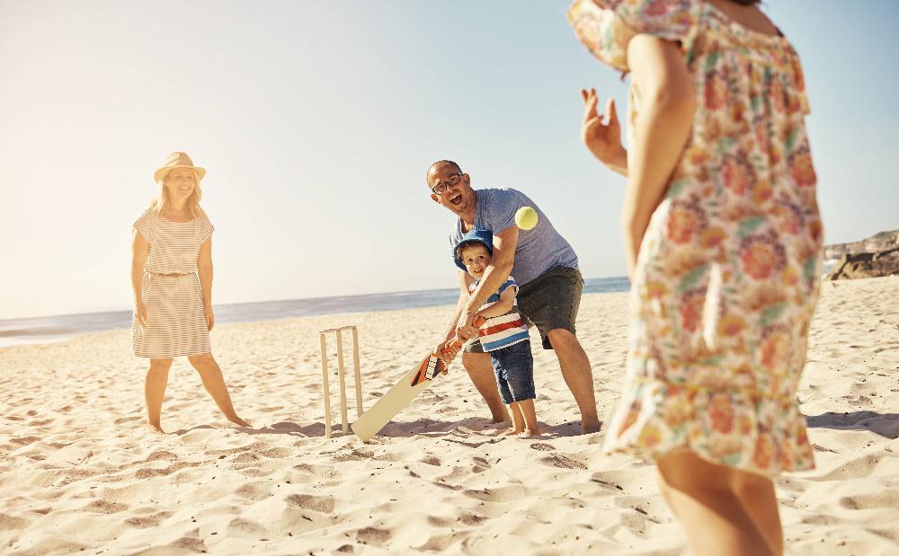 Family playing cricket on beach