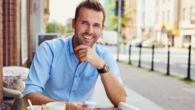 man smiling while sitting outside cafe in mirrabooka