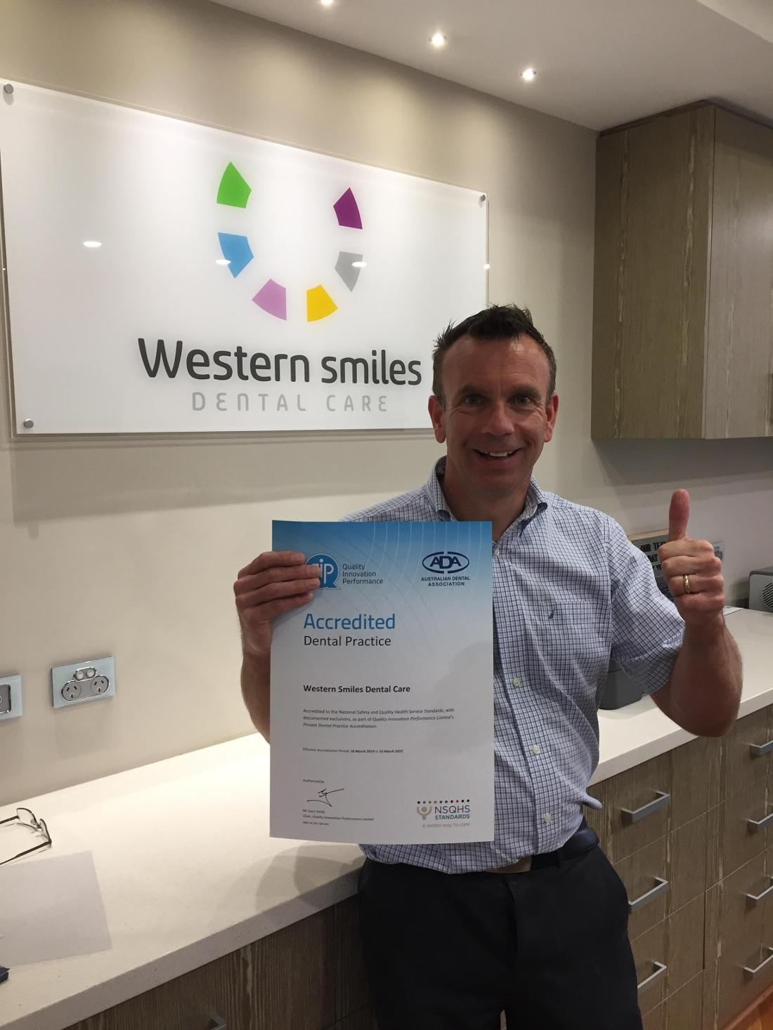 Dr Peter holding Western Smiles QIP accreditation certificate