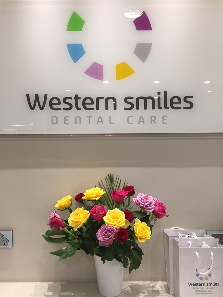 Vase of multi-color roses sitting below main Wester Smiles Dental Care logo